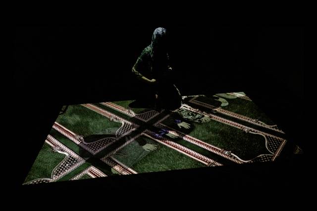 A member of the congregation interacts with the moving projection in the female prayer room in Brick Lane Mosque during a site performance